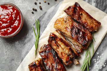 Delicious grilled ribs served on grey table, flat lay