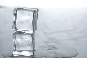 Wet ice cubes on white table, closeup. Space for text