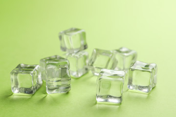 Crystal clear ice cubes on light green background