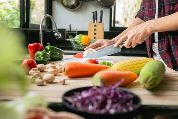 Close-up man cooking and slicing fresh vegetables on a rustic kitchen worktop, healthy eating concept, flat lay