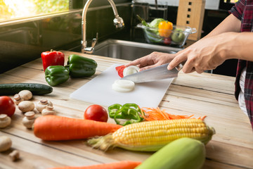 Close-up man cooking and slicing fresh vegetables on a rustic kitchen worktop, healthy eating concept, flat lay