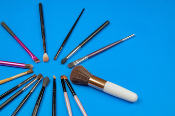 Set of various make up brushes on a blue background