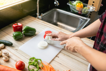 Close-up man cooking and slicing fresh vegetables on a rustic kitchen worktop, healthy eating concept, flat lay