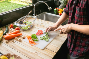 Close-up man cooking and slicing fresh vegetables on a rustic kitchen worktop, healthy eating concept, flat lay