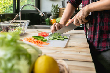 Close-up man cooking and slicing fresh vegetables on a rustic kitchen worktop, healthy eating concept, flat lay