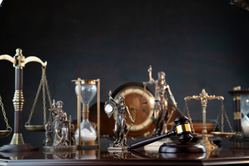 Obraz na płótnie Canvas Law and justice theme. Judge’s gavel, Themis statue, scale, hourglass and old clock on the shining wooden brown table and the gray background.