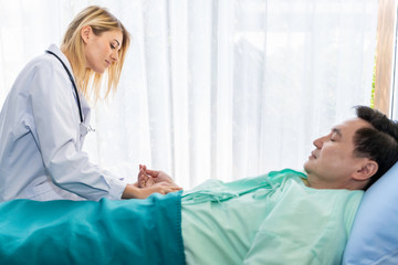 Medical professionals Caucasian woman take the pulse with  man patient in the hospital room.