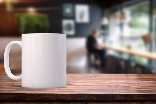 White coffee Mug Mockup set-up in a cafe, with blurred background. Great for overlaying your custom quotes and designs for selling mugs.