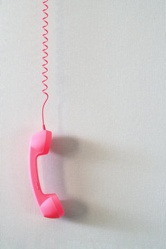 Pink telephone receiver on a light background