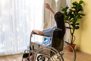 Asian woman patient sitting in the wheelchair at hospital room.
