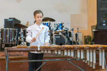 Teenager girl in a white shirt boy playing the marimba