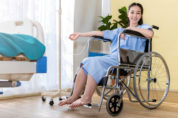 Asian woman patient sitting in the wheelchair at hospital room.