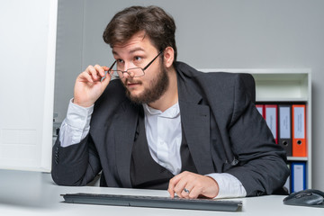employed has trouble reading the monitor content and looks over his glasses