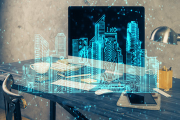 Desktop computer background in office and big town buildings hologram drawing. Double exposure. Smart city concept.