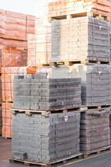 Several pallets with concrete brick stacked on top of each other in depot. Industrial production of bricks. vertical photo