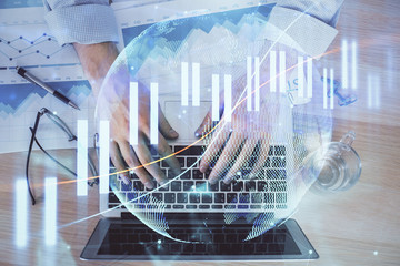 Double exposure of market chart with man working on computer on background. Concept of financial...