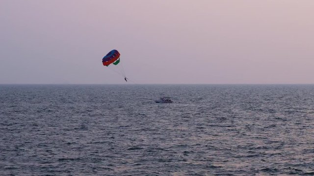 parasailing over the blue sea at sunset