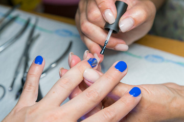 Beautiful manicure process. Nail polish being applied to hand, polish is a blue color. close up. 2020 color