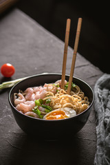 Asian soup with noodles, greens and shrimps on dark background