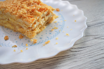 Napoleon cake with vanilla milk cream on a plate isolated on white background