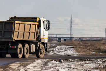 An old, dirty dump truck turns off the main road