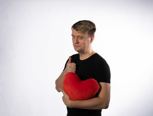 The guy is holding in his hands a heart greetings for Valentines day on white background