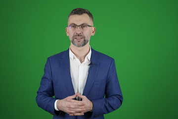 A blogger is recording a video on a green background.  The camcorder is recording a blogger.
