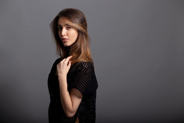 Beauty portrait of a sensual young woman in black, with natural makeup, isolated on a grey background.