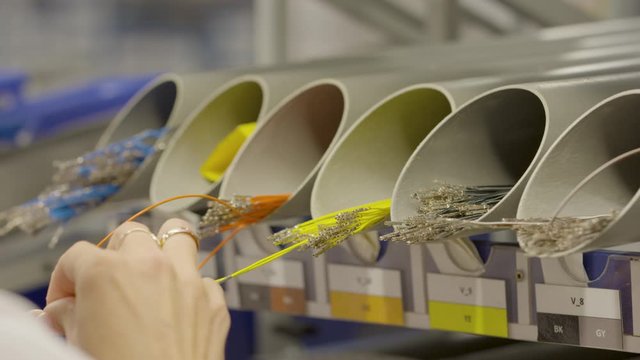car electronics cable manufacturing plant, closeup on the hands that make up the cable