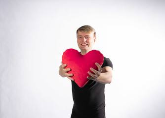 The guy is holding in his hands a heart for the happiness of Valentines day on white background