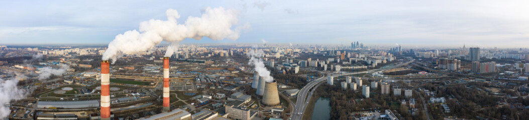 power plant pipes and cooling towers on the background of the panorama of the winter city against...