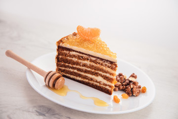 Cake with honey, golden pearls and mint leaf on a plate isolated over white background