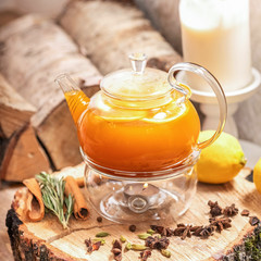 Sea Buckthorn tea candle basking. Vitaminic healthy sea buckthorn tea with cinnamon sticks, lemon, rosemary, honey on wooden background.