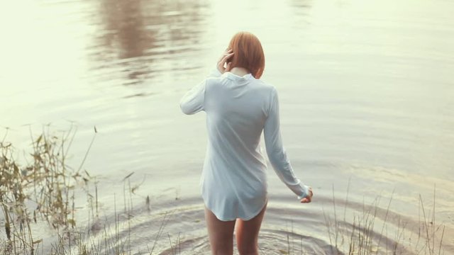 Girl with red hair standing dressed shirt in lake