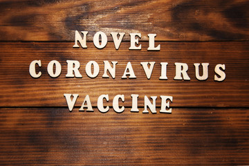 Text Novel Coronavirus Vaccine on dark wooden table background. Virus Pandemic Protection Concept.