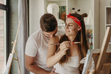 Love story of a beautiful couple in an art studio. They paint pictures, laugh, kiss each other. Their emotions, feelings, love. © sushytska