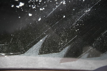 Squeegee frosted windshield in the morning