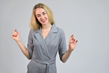 Model Standing directly in front of the camera in various poses. Portrait of a pretty cute smiling young blonde business woman with minimal makeup in a gray suit on a white background.