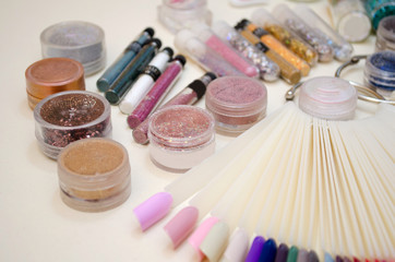 Naklejka premium Jars with sparkles and decor for nail design, color samples of gel polish on a plastic tips closeup