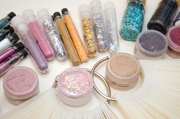 Jars with sparkles and decor for nail design, color samples of gel polish on a plastic tips closeup