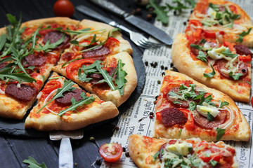 Italian cuisine concept, pizza pepperoni with sausage and arugula on a dark wooden background