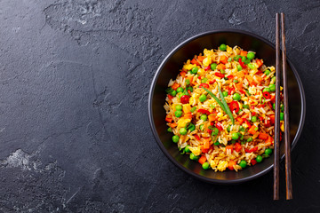 Asian fried rice with egg and vegetables. Black background. Cope space. Top view.