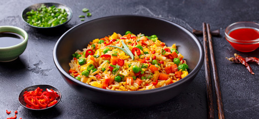 Asian fried rice with egg and vegetables. Dark stone background. Close up.