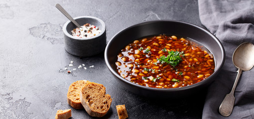 Bean soup in a black bowl. Black background. Copy space.