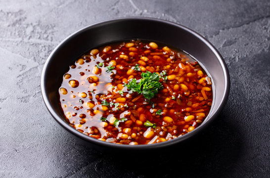 Bean soup in a black bowl. Dark background. Close up.