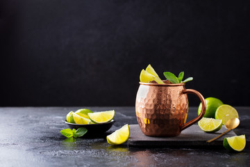 Cold Moscow Mules cocktail with ginger beer, vodka, lime and mint. Grey stone background. Copy space.