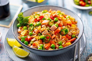Asian fried rice with pork ham. Blue wooden background. Close up.