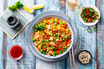 Asian fried rice with pork ham. Blue wooden background. Top view.
