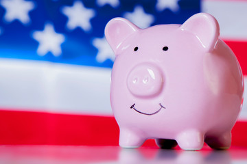 Concept: in USA anyone can become successful and rich. Piggy bank in front of US flag.