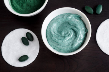 Spirulina and yogurt facial mask in the small white bowl. Natural beauty treatment and spa recipe. Close up, top view, copy space.
